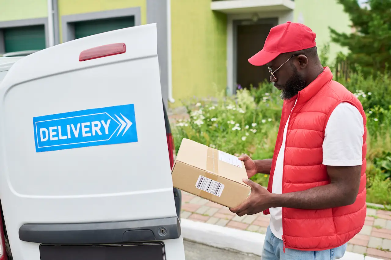delivery man holding a cardboard package next to a 2026 09 25 07 07 13 utc